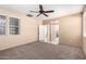 This bedroom features a ceiling fan, carpeted floor, and leads into a bathroom with white door at 4061 N Point Ridge Rd, Buckeye, AZ 85396