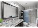 Updated bathroom featuring gray tiled walls, glass shower door, and marble countertop with modern vanity at 4440 W Fallen Leaf Ln, Glendale, AZ 85310