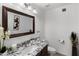 Neat powder room with dark wood vanity, white sink, and ornate framed mirror adds a touch of elegance at 4440 W Fallen Leaf Ln, Glendale, AZ 85310