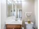 Bathroom featuring a wood vanity, white sink and toilet, and a large mirror at 7421 S 25Th Ln, Phoenix, AZ 85041