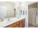 Bathroom with a double sink vanity, mirrors, and a shower with a floral curtain at 7421 S 25Th Ln, Phoenix, AZ 85041