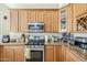 Kitchen with stainless steel range, granite countertops, and warm wood cabinetry at 7421 S 25Th Ln, Phoenix, AZ 85041