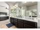 Bathroom with double vanity, undermount sinks, a large mirror, dark wood cabinets, and views into the main bedroom at 7693 E Via Del Sol Dr, Scottsdale, AZ 85255