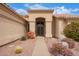 Inviting front entrance featuring an arched doorway and desert landscaping with vibrant plants and decorative rocks at 9104 E Hillery Dr, Scottsdale, AZ 85260