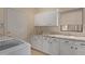 Well-lit laundry room with white cabinets, granite counters, a stainless steel faucet, and modern appliances at 9104 E Hillery Dr, Scottsdale, AZ 85260