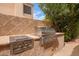 Outdoor kitchen features built-in grill station with stainless steel appliances and textured stone construction at 9104 E Hillery Dr, Scottsdale, AZ 85260