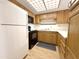 Galley kitchen featuring wood cabinets, black appliances, and a drop ceiling at 10330 W Thunderbird Blvd # B101, Sun City, AZ 85351