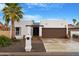 Charming single-story home with desert landscaping, palm tree and a two-car garage in a gated community at 10406 E Silvertree Dr, Sun Lakes, AZ 85248