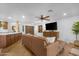 Cozy living room with open layout, featuring wood-look floors, leather couch, and kitchen island at 10406 E Silvertree Dr, Sun Lakes, AZ 85248