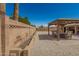 Backyard with gravel and brick-paved patio features a gazebo with seating, a wall, and trees at 10718 W Saratoga Cir, Sun City, AZ 85351