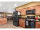 Bright kitchen with tile floors, wood cabinets, black appliances, and access to the living room at 10718 W Saratoga Cir, Sun City, AZ 85351