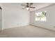 Bright bedroom with neutral carpet, large window, and ceiling fan at 11451 S Half Moon Dr, Phoenix, AZ 85044