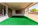 Covered patio with green turf offers a view of sliding glass doors and a backyard with trees and privacy wall at 11451 S Half Moon Dr, Phoenix, AZ 85044