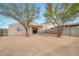 Exterior view of the home with a spacious backyard and mature trees at 11765 W Maui Ln, El Mirage, AZ 85335