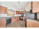 Kitchen featuring wood cabinets, tile countertops, black appliances, and tile flooring at 11765 W Maui Ln, El Mirage, AZ 85335