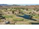 Aerial view of a lush golf course with scenic greens, a tranquil pond, and views of the surrounding mountains at 12231 S 185Th Ave, Goodyear, AZ 85338