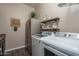 Bright laundry room features modern washer and dryer, stainless steel refrigerator, and wooden shelving at 12231 S 185Th Ave, Goodyear, AZ 85338