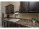 Mud room featuring a white sink, dark cabinets, dark countertops and walls painted in a neutral tone at 12231 S 185Th Ave, Goodyear, AZ 85338