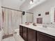 Bathroom with neutral tile floor, dark cabinets, shower with curtain, and a large mirror at 18556 W Vogel Ave, Goodyear, AZ 85338