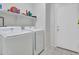 Bright laundry room with modern white washer and dryer units and a white shelving unit at 18556 W Vogel Ave, Goodyear, AZ 85338