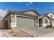 Attractive exterior with desert landscaping, complemented by a well-maintained green two-car garage at 21743 N Daniel Dr, Maricopa, AZ 85138