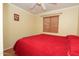 Simple bedroom with red bedding, ceiling fan and bright window with laminate flooring at 2201 W Wethersfield Rd, Phoenix, AZ 85029