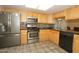 Well-lit kitchen equipped with stainless steel appliances, wooden cabinets, and gray tile at 2201 W Wethersfield Rd, Phoenix, AZ 85029