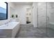 A well-lit bathroom features a soaking tub, glass shower and modern gray hexagon tile at 23880 N 127Th St, Scottsdale, AZ 85255