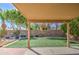 View from under a covered patio of backyard with artificial grass, brick, mature trees, and a privacy wall beyond at 2560 S Rowen --, Mesa, AZ 85209