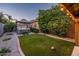 Landscaped backyard with a hot tub under a covered patio, artificial turf, and mature trees at 2678 S 172Nd Dr, Goodyear, AZ 85338