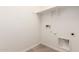 This laundry room with vinyl floors and white walls, features shelving, water connections, and electrical outlets at 5352 W Las Palmaritas Dr, Glendale, AZ 85302
