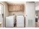 Laundry room with white washer and dryer, overhead cabinets and light-colored wood floors at 5402 E Mckellips Rd # 326, Mesa, AZ 85215