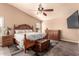 Charming main bedroom featuring a wooden bed frame, ceiling fan, and an entertainment center at 5929 W Riviera Dr, Glendale, AZ 85304