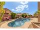 Private backyard swimming pool with lush landscaping, outdoor dining area, and beautiful blue skies at 5929 W Riviera Dr, Glendale, AZ 85304