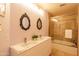 Pink bathroom featuring a dual sink vanity, decorative mirrors, and a shower-tub combo at 7826 W Kerry Ln, Glendale, AZ 85308