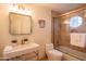 Well-lit bathroom featuring a shower and tub combination with glass doors and a modern vessel sink at 7826 W Kerry Ln, Glendale, AZ 85308