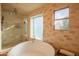 Bright bathroom featuring a soaking tub, glass shower, travertine tile, and a view to the outdoors at 7826 W Kerry Ln, Glendale, AZ 85308