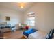 Bedroom with wood floors, a small bed, desk and chair near a window with bamboo blinds at 7826 W Kerry Ln, Glendale, AZ 85308