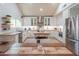 Open kitchen with travertine floors, island, stainless steel appliances, and white cabinetry at 7826 W Kerry Ln, Glendale, AZ 85308