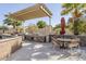 Outdoor kitchen and BBQ area with seating, grill, and pergola in a landscaped setting at 9409 W Taro Ln, Peoria, AZ 85382