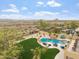 An aerial shot of the backyard showing a beautiful pool, patio, waterfall feature, lush green yard and desert landscape at 9686 W Keyser Dr, Peoria, AZ 85383