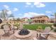 An outdoor oasis featuring a charming brick firepit, lush green grass, a swimming pool and a patio with plenty of seating at 9686 W Keyser Dr, Peoria, AZ 85383