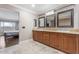 Bathroom with double sink, tiled floors, and access to a well-lit bedroom with a view at 9686 W Keyser Dr, Peoria, AZ 85383