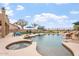 Relaxing backyard featuring a pool with rock waterfall, a spa, and lounge seating under blue umbrellas at 9686 W Keyser Dr, Peoria, AZ 85383