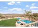 Inviting backyard featuring a sparkling pool, lush green lawn, desert landscaping, and mountain views at 9686 W Keyser Dr, Peoria, AZ 85383