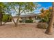 Charming single-story home with desert landscaping, mature trees, and solar panels at 9918 W Willow Creek Cir, Sun City, AZ 85373