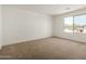 Bedroom featuring neutral carpeting, white walls, and a large window, providing ample natural light at 11605 W Green Dr, Youngtown, AZ 85363