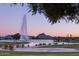 A serene lake view at dusk featuring a fountain, mountain backdrop, and landscaped park with walking path at 15510 E Sycamore Dr, Fountain Hills, AZ 85268