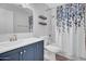 A bathroom with a white toilet, blue vanity, decorative shower curtain, and wood-look decorative shelves at 1717 E Sandra Ter, Phoenix, AZ 85022