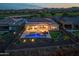 Aerial view of backyard featuring a pool, fire pit, and putting green at dusk at 18016 E Wolf Tree Ln, Rio Verde, AZ 85263